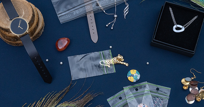 Un assortiment de bijoux et montres emballés dans des sachets plastiques refermables, disposés sur une table, illustrant les solutions d'emballage écoresponsables pour la joaillerie.